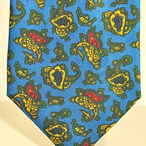 Può includere: Una cravatta di seta blu con un motivo paisley in giallo, verde e rosso.