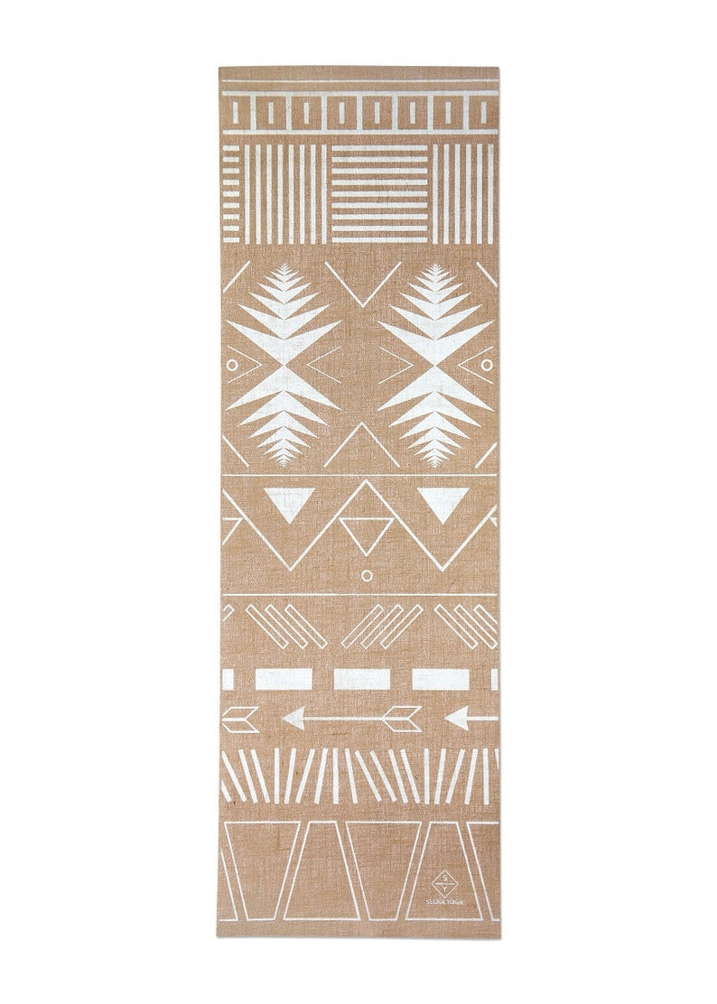May include: A brown yoga mat with a white geometric pattern. The pattern includes triangles, arrows, and lines. The mat has the text "Studio Yoga" printed on the bottom right corner.