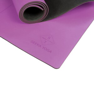 Pu&ograve; includere: Tappetino da yoga viola con una superficie antiscivolo nera. Il tappetino &egrave; arrotolato e presenta il logo "SEEKA YOGA" con una "Y" stilizzata e un design a spada.