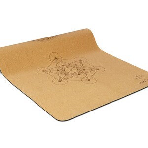 May include: A brown cork yoga mat with a geometric design printed on it. The mat is rolled up and has a black edge. The text "Soma Yoga" is printed on the mat.