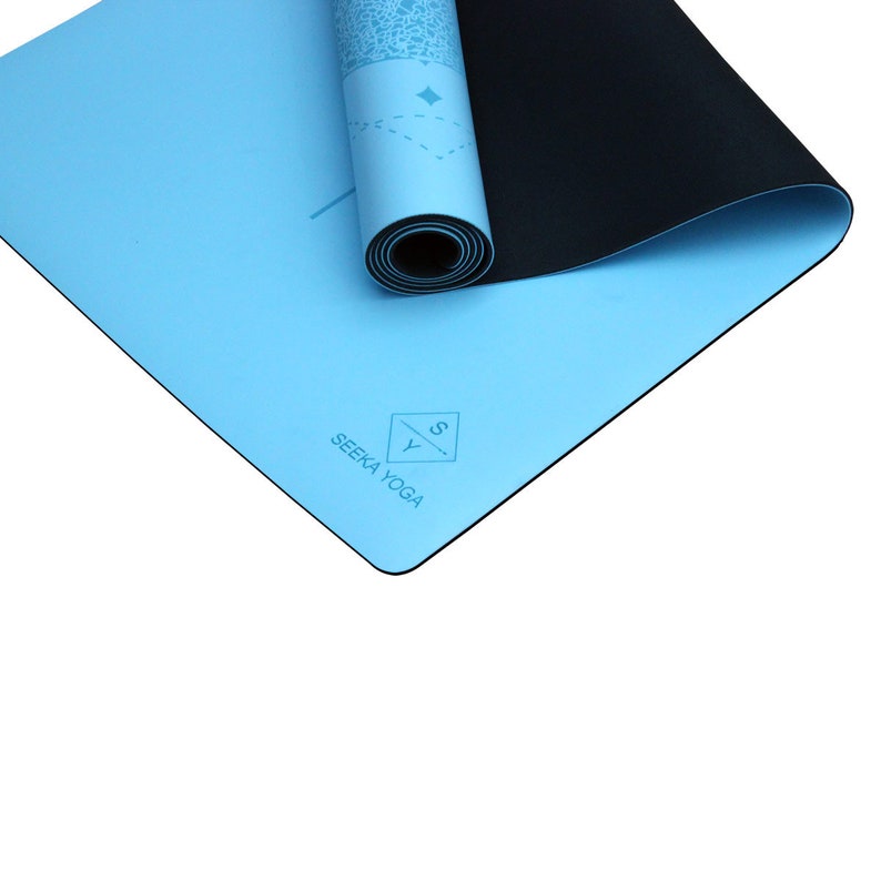 May include: A light blue yoga mat with a black underside. The mat is rolled up and has a logo that says "SEEKA YOGA" with a stylized "S" and "Y" in a diamond shape.