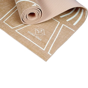 May include: A rolled-up light pink yoga mat with a tan jute mat underneath. The jute mat has a white geometric pattern and the text "SEEKA YOGA" printed on it.