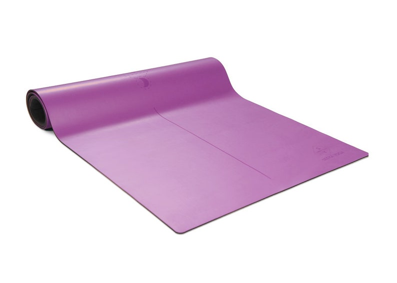 Pu&ograve; includere: Un tappetino da yoga viola con una superficie leggermente testurizzata. Il tappetino &egrave; arrotolato e ha un cinturino nero.