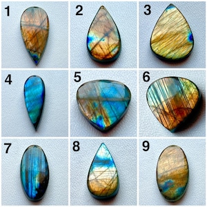 Pode incluir: Nove pedras preciosas de labradorite polidas em várias formas, incluindo gota, oval e triangular. As pedras exibem flashes iridescentes de azul, dourado e laranja. Cada pedra é única, mostrando padrões e cores naturais. Ideal para joalheria ou colecionismo.