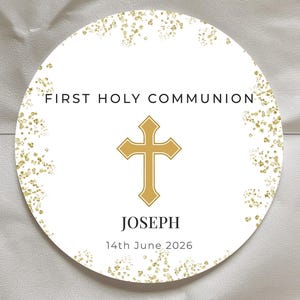 Könnte beinhalten: Ein runder, weißer Aufkleber mit goldenen Akzenten und Text. Oben steht "FIRST HOLY COMMUNION", in der Mitte ein goldenes Kreuz. Darunter der Name "JOSEPH" und das Datum "14. Juni 2026".