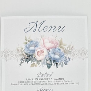 May include: A light blue and pink floral design with a white background. The text "Menu" is at the top of the image. The text "Salad" is below the floral design. The text "APPLE, CRANBERRY & WALNUT" is below the word "Salad". The text "(FIELD GREENS TOSSED WITH SWEET APPLES, PECANS, DRIED CHERRIES, GORGONZOLA CHEESE, AND HONEY VINAIGRETTE)" is below the text "APPLE, CRANBERRY & WALNUT". The text "Scones" is at the bottom of the image.