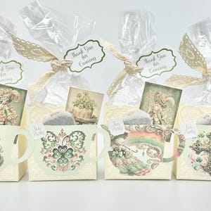 May include: Four small, white, teacup-shaped boxes with green and gold designs. Each box contains a tea bag and a small card with the text "Thank You for Coming".