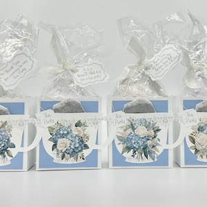 May include: Six blue and white teacup-shaped gift boxes with floral designs and a white ribbon. Each box has a tag that says "Thank you for being a part of our wedding day!"