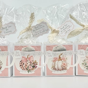 May include: Four small white boxes with pink accents, each containing a tea bag and decorated with a teacup design featuring a pumpkin and floral accents. The boxes have a "Tea Party" label and come with a thank you tag.