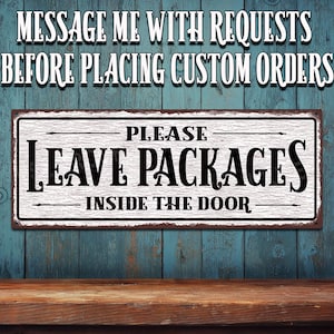 May include: A rectangular sign with the text "PLEASE LEAVE PACKAGES INSIDE THE DOOR" in black letters on a white background. The sign also has the text "MESSAGE ME WITH REQUESTS BEFORE PLACING CUSTOM ORDERS" in white letters. The sign is framed with a brown border.