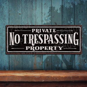 May include: A black and white metal sign with the text "PRIVATE PROPERTY NO TRESPASSING" in white lettering on a black background.