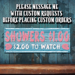 May include: A rectangular sign with the text "SHOWERS $1.00" in pink letters on a blue background. The sign also includes the text "$2.00 TO WATCH" and "PLEASE MESSAGE ME WITH CUSTOM REQUESTS BEFORE PLACING CUSTOM ORDERS".