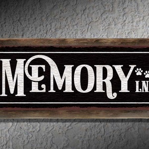 May include: A rustic wooden sign with black background and white lettering that reads "MEMORY LN." with three paw prints.