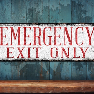 May include: White sign with red text that reads "EMERGENCY EXIT ONLY" on a blue wooden background.