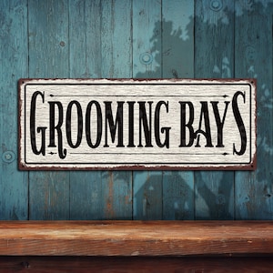 May include: White metal sign with black text that reads "Grooming Bay's" on a blue wood background.