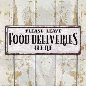 May include: White metal sign with distressed paint and brown edges. The sign reads "PLEASE LEAVE FOOD DELIVERIES HERE" in black lettering.