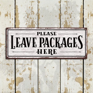 May include: White metal sign with distressed paint and brown edges. The sign reads "PLEASE LEAVE PACKAGES HERE" in black lettering with a vintage font.