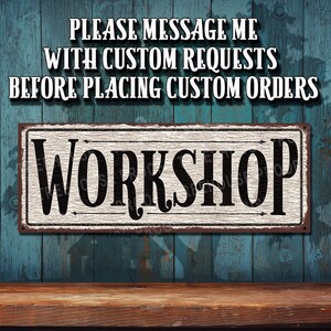 May include: A white sign with black lettering that reads "Workshop". The sign is on a blue wooden background with the text "Please message me with custom requests before placing custom orders" above it.
