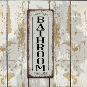May include: A vertical wooden sign with a distressed white background and black lettering that reads "BATHROOM". The sign has a red border and decorative flourishes at the top and bottom.