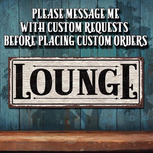 May include: A rustic, white sign with black lettering that reads "LOUNGE". The sign has a distressed, vintage look and is perfect for adding a touch of rustic charm to any space.