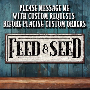 May include: A rectangular metal sign with the words "FEED & SEED" in bold black letters. The sign has a distressed, rustic look with a white background and a brown border. The text "PLEASE MESSAGE ME WITH CUSTOM REQUESTS BEFORE PLACING CUSTOM ORDERS" is above the sign.