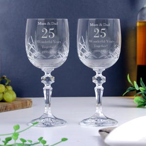 May include: Two clear crystal wine glasses with etched designs. The glasses are engraved with the text "Mum & Dad 25 Wonderful Years Together! 1999-2021".