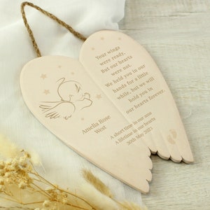 May include: A wooden heart-shaped ornament with angel wings, a small angel figure, and the text "Your wings were ready, But our hearts were not. We held you in our hands for a little while, but we will hold you in our hearts forever. Amelia Rose West A short time in our arms A lifetime in our hearts 30th May 2023".