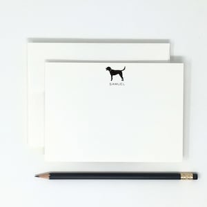 May include: A white card with a black silhouette of a dog and the name "SAMUEL" printed below it.