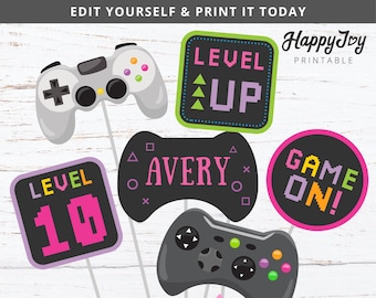 Può includere: Un set di sei accessori per foto booth stampabili a tema gioco. Gli accessori presentano uno schema di colori rosa e nero con accenti verdi e gialli. Gli accessori includono un controller di gioco, un cartello "livello superiore", un cartello "livello 10", un cartello "gioco in corso" e un cartello che dice "Avery".