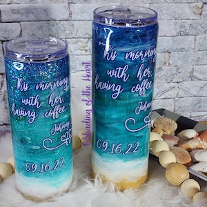 May include: Two blue and white glitter tumblers with the text "his morning with her having coffee" and the date "09.16.22". The tumblers have a beach scene with waves and sand.