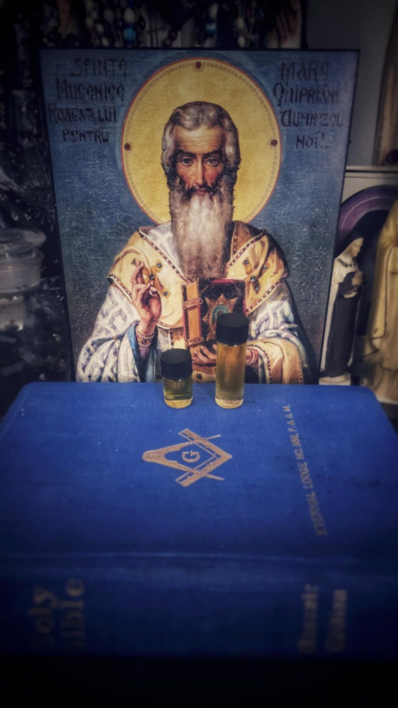 May include: An image featuring a religious icon with Romanian text and a Masonic symbol. Two small glass bottles with black lids are on a blue book. The bottles contain a light amber liquid.