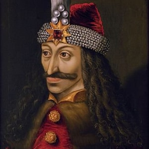 May include: Portrait of a man in a red coat with gold buttons and a fur collar. He wears a jeweled hat with a red cap and a star-shaped ornament. The man has a long mustache and dark, curly hair.