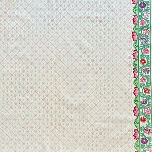 May include: A white fabric with a pink diamond pattern and a green and pink floral border. The floral border features pink, green, and purple flowers.