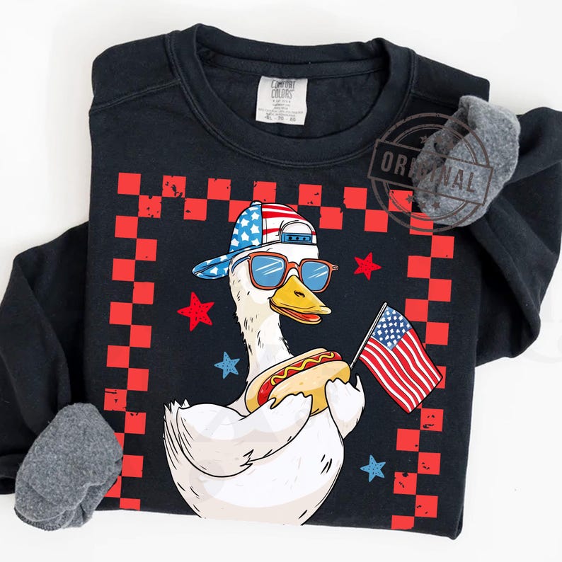 May include: A white duck wearing a red, white, and blue baseball cap and sunglasses, holding a hot dog in one hand and an American flag in the other. The duck is standing on a black and red checkered background.