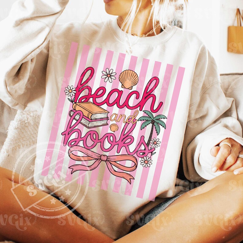 Puede incluir: Sudadera color crema con un dise&ntilde;o de rayas rosas y blancas. El gr&aacute;fico dice "beach and books" en escritura rosa, con ilustraciones de un libro, una concha, una palmera y flores.