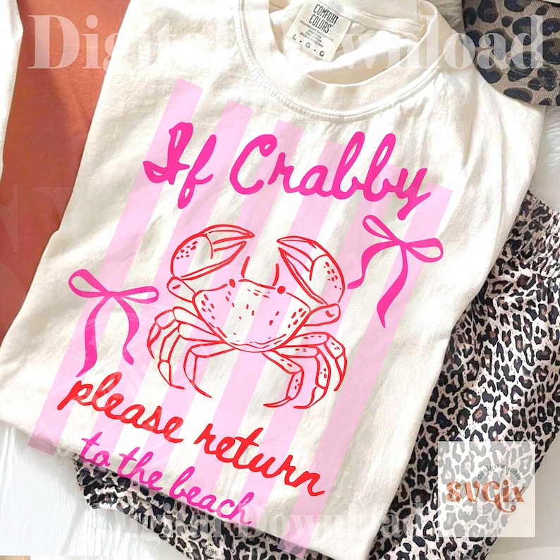 May include: Cream-colored t-shirt with a pink crab graphic and the text "If Crabby please return to the beach." The design includes pink vertical stripes and bows. The shirt is paired with leopard print pants.