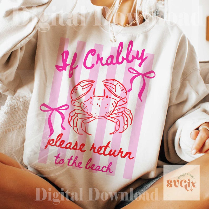 May include: A white sweatshirt with a pink crab graphic and the text "If Crabby please return to the beach." The design includes pink vertical stripes and bows. The sweatshirt is a casual, beach-themed apparel item.