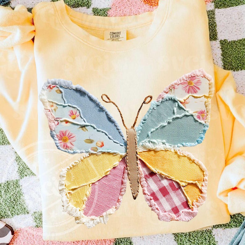 May include: A light yellow Comfort Colors sweatshirt featuring a large, patchwork butterfly applique. The butterfly wings are made of various patterned fabrics in blue, pink, yellow, and floral prints. The sweatshirt has a crew neck and long sleeves.