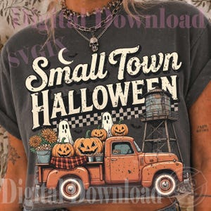 May include: A charcoal gray t-shirt featuring a graphic print with the text Small Town HALLOWEEN. The design includes an orange pickup truck carrying pumpkins, ghosts, and a water tower, set against a checkered background with bats and a crescent moon.