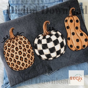 May include: Three decorative pumpkins with unique patterns are displayed on a dark gray surface. One pumpkin has a leopard print, another features a black and white checkerboard design, and the third has large black polka dots.