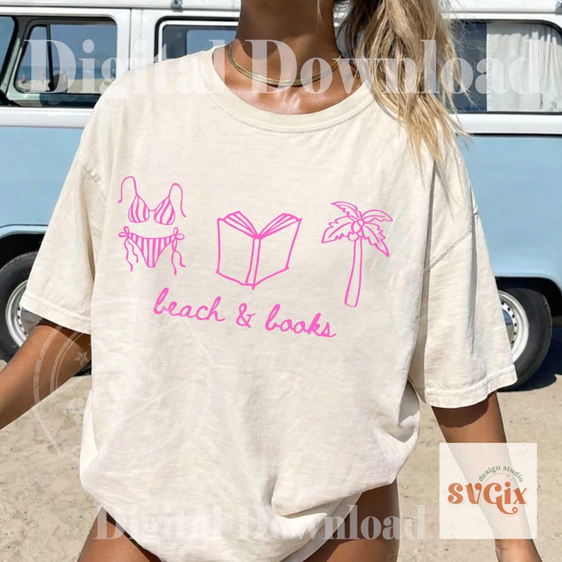 K&ouml;nnte beinhalten: Cremefarbenes T-Shirt mit einer rosa Grafik eines Bikinis, eines offenen Buches und einer Palme. Die Worte "beach & books" sind in rosa Schrift darunter geschrieben. Das Shirt hat kurze &Auml;rmel.
