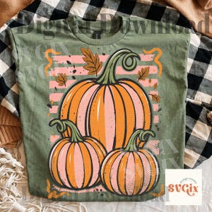 May include: Green t-shirt featuring a pumpkin design. The design includes three pumpkins in shades of orange and pink, with green stems and leaves. The text "Digital Download" is visible.