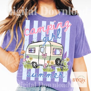 May include: A lilac t-shirt with a camping theme. The shirt features a camper illustration with the words "camping girl summer" in pink and blue script. The camper is surrounded by flowers and grass.