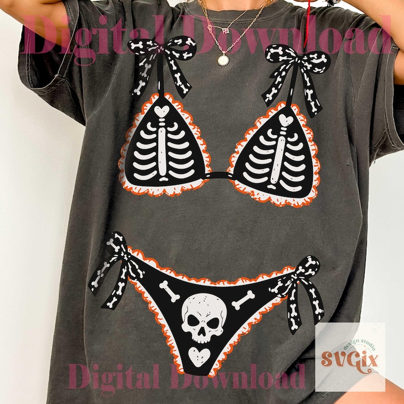 Peut inclure: Un t-shirt gris anthracite arborant un imprim&eacute; graphique repr&eacute;sentant un bikini noir avec des d&eacute;tails de cage thoracique squelettique blanche sur le haut et un motif de cr&acirc;ne sur le bas, agr&eacute;ment&eacute; de bords &agrave; volants orange et de n&oelig;uds &agrave; motifs d'os.