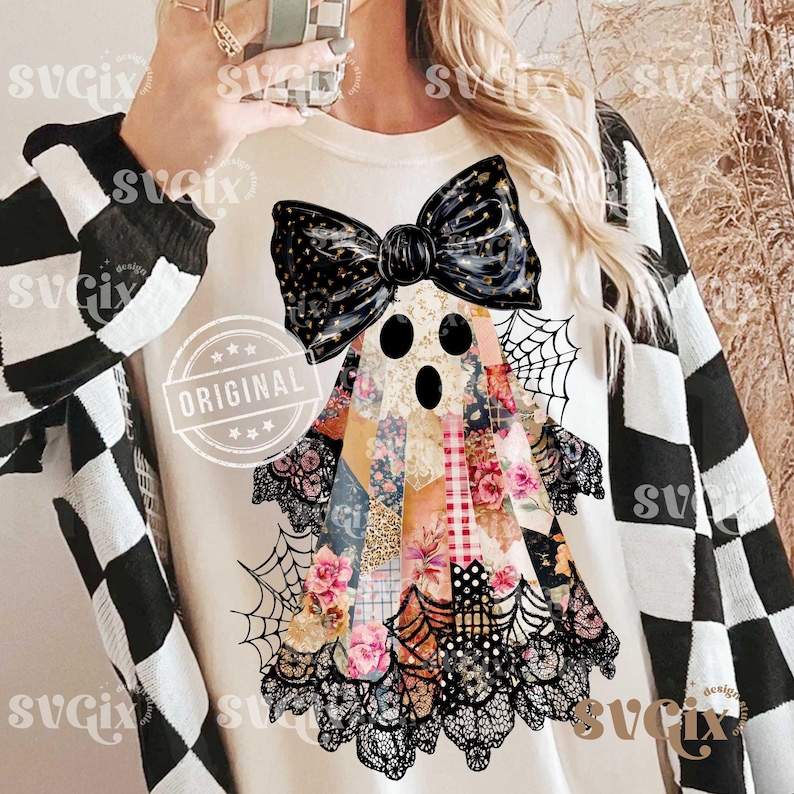 May include: Cream-colored Halloween-themed t-shirt featuring a patchwork ghost design with a black bow, lace trim, and spiderwebs. The ghost's body is made of floral and patterned fabrics. The word "ORIGINAL" is stamped on the shirt.