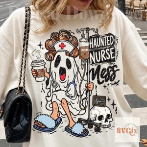 Puede incluir: Una sudadera color crema con un gr&aacute;fico de un fantasma vestido de enfermero con rulos, sosteniendo una taza de caf&eacute; y un soporte de suero. El texto dice Haunted Nurse Mess y Caffeine. Tambi&eacute;n se representan un cr&aacute;neo y un monitor card&iacute;aco.
