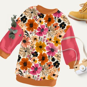 May include: A long-sleeved sweatshirt with a floral pattern in shades of orange, pink, black, and yellow. The sleeves are a solid coral color with brown trim. A yellow boot is in the upper right corner.