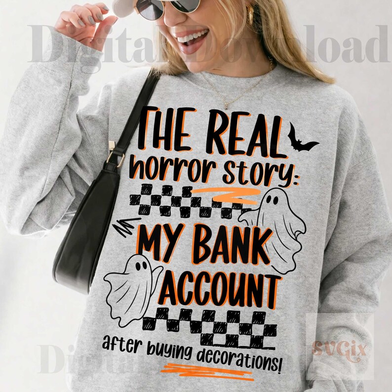 Pode incluir: Camisola cinzenta com o texto "THE REAL horror story: MY BANK ACCOUNT after buying decorations!" em preto e laranja. O design inclui um morcego, duas ilustra&ccedil;&otilde;es de fantasmas e um padr&atilde;o xadrez, ideal para o Halloween.