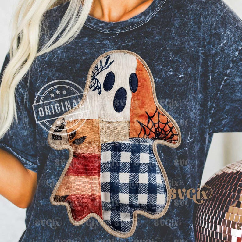 May include: Dark blue t-shirt featuring a patchwork ghost design. The ghost is composed of various fabric patterns, including white, orange, plaid, and floral prints. The word "ORIGINAL" is printed on the shirt. The shirt has a round neckline.