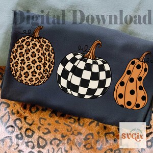 Puede incluir: Tres calabazas decorativas con dise&ntilde;os &uacute;nicos. Una calabaza tiene estampado de leopardo, otra presenta un dise&ntilde;o de tablero de ajedrez en blanco y negro, y la tercera es naranja con lunares negros. Las palabras "Digital Download" est&aacute;n en la parte superior.